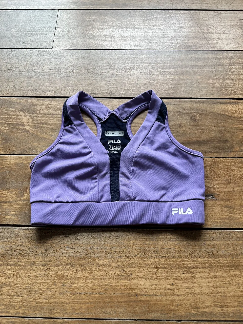 Top deportivo Fila color violeta con detalles en negro. Ideal para entrenamientos de alto impacto. Talle S.