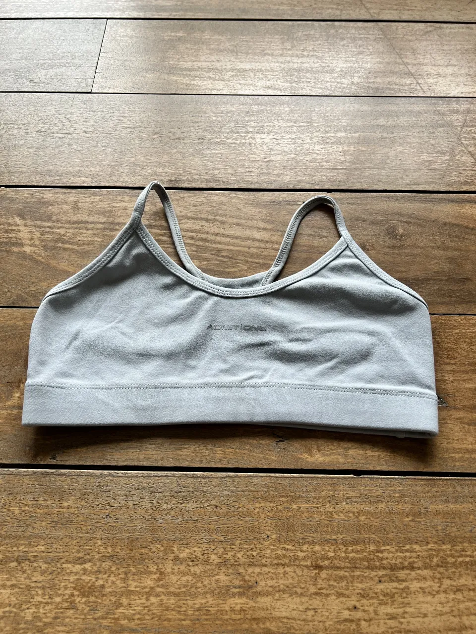 Top deportivo gris claro, ideal para entrenamientos. Confeccionado con tela suave y diseño minimalista. Perfecto para combinar con calzas o shorts.