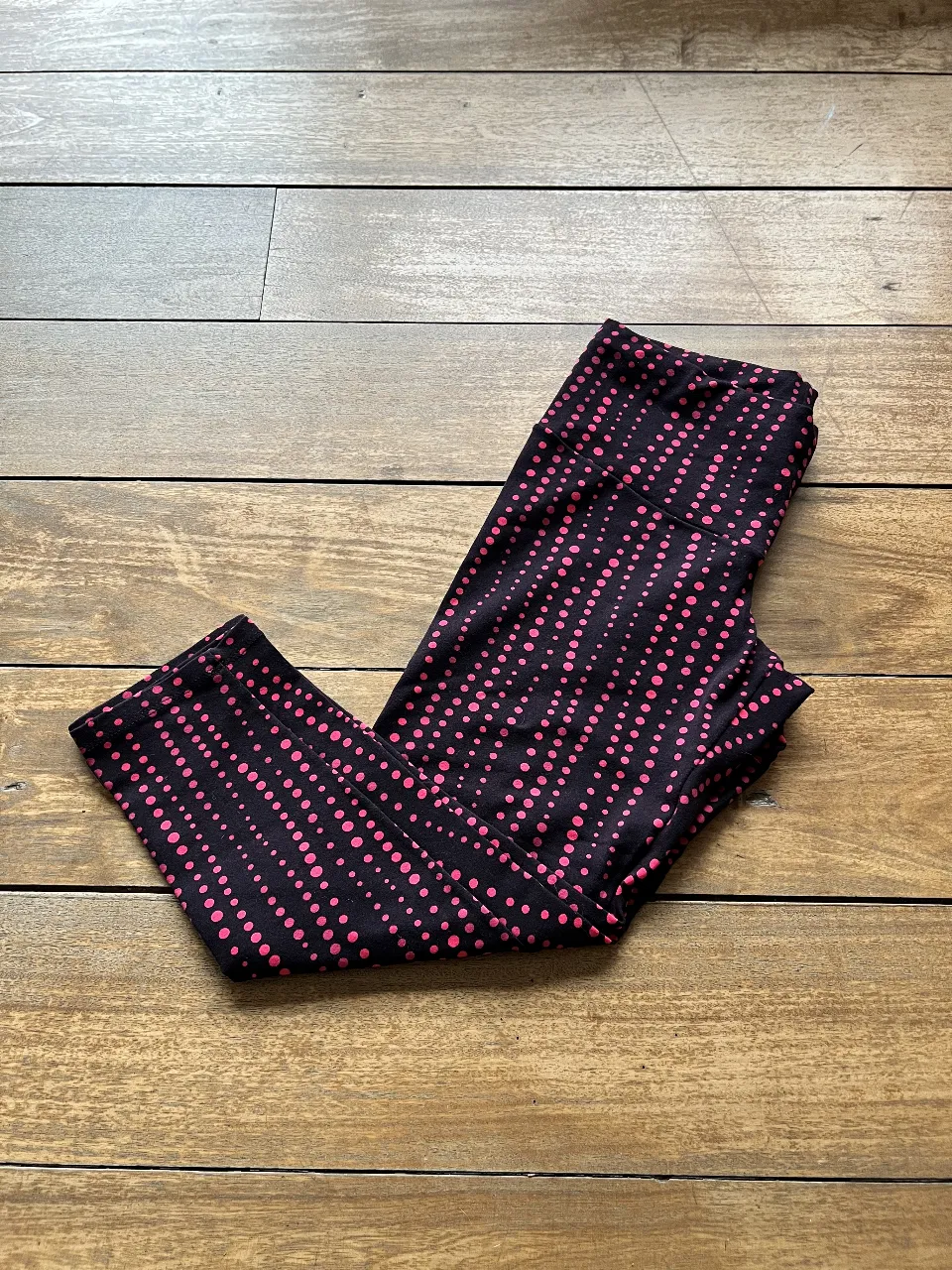 Calzas deportivas de mujer, con estampado de lunares en color rosa y fucsia sobre fondo negro. ideales para actividades físicas o uso casual.