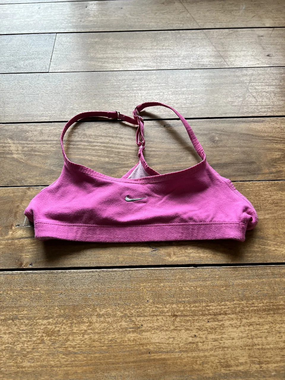 Top deportivo Nike rosa, ideal para actividades de bajo impacto. Con logo de la marca y diseño de espalda estilo nadador.