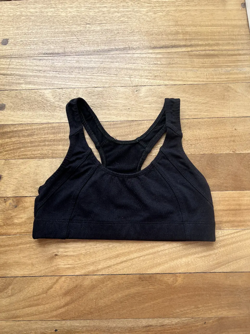 Top deportivo negro, ideal para actividades de bajo impacto. Con diseño de espalda deportiva y detalle de marca "ONE STEP". Perfecto para entrenamientos cómodos y con estilo.