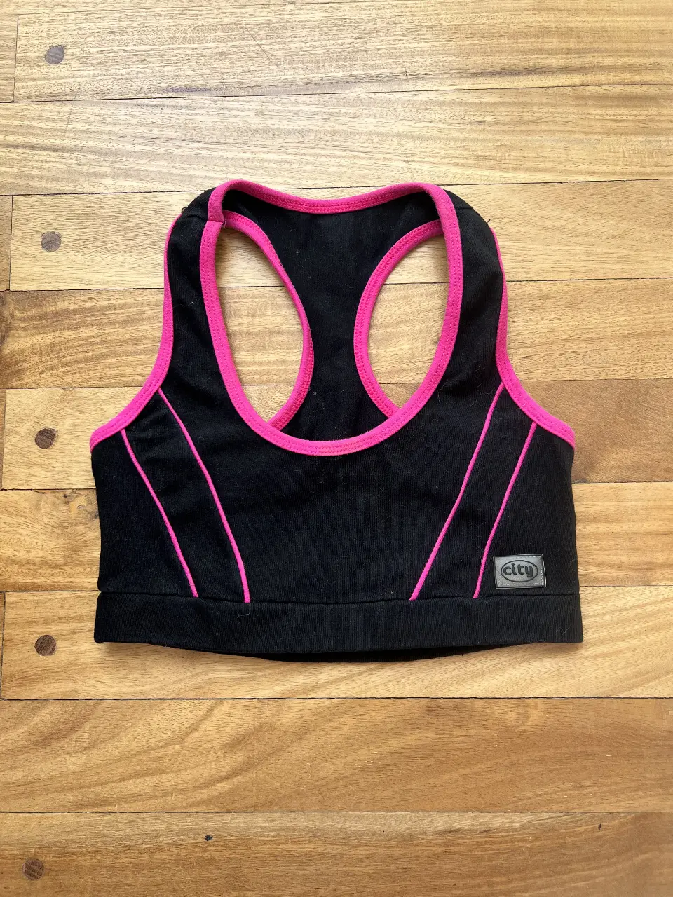 Top deportivo negro con detalles en rosa, ideal para entrenamientos. Marca City Sport.