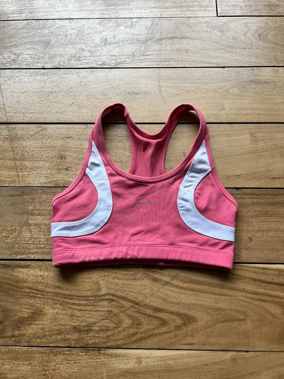 Top deportivo rosa con detalles en blanco. Ideal para actividades de bajo impacto. Diseño cómodo y femenino.