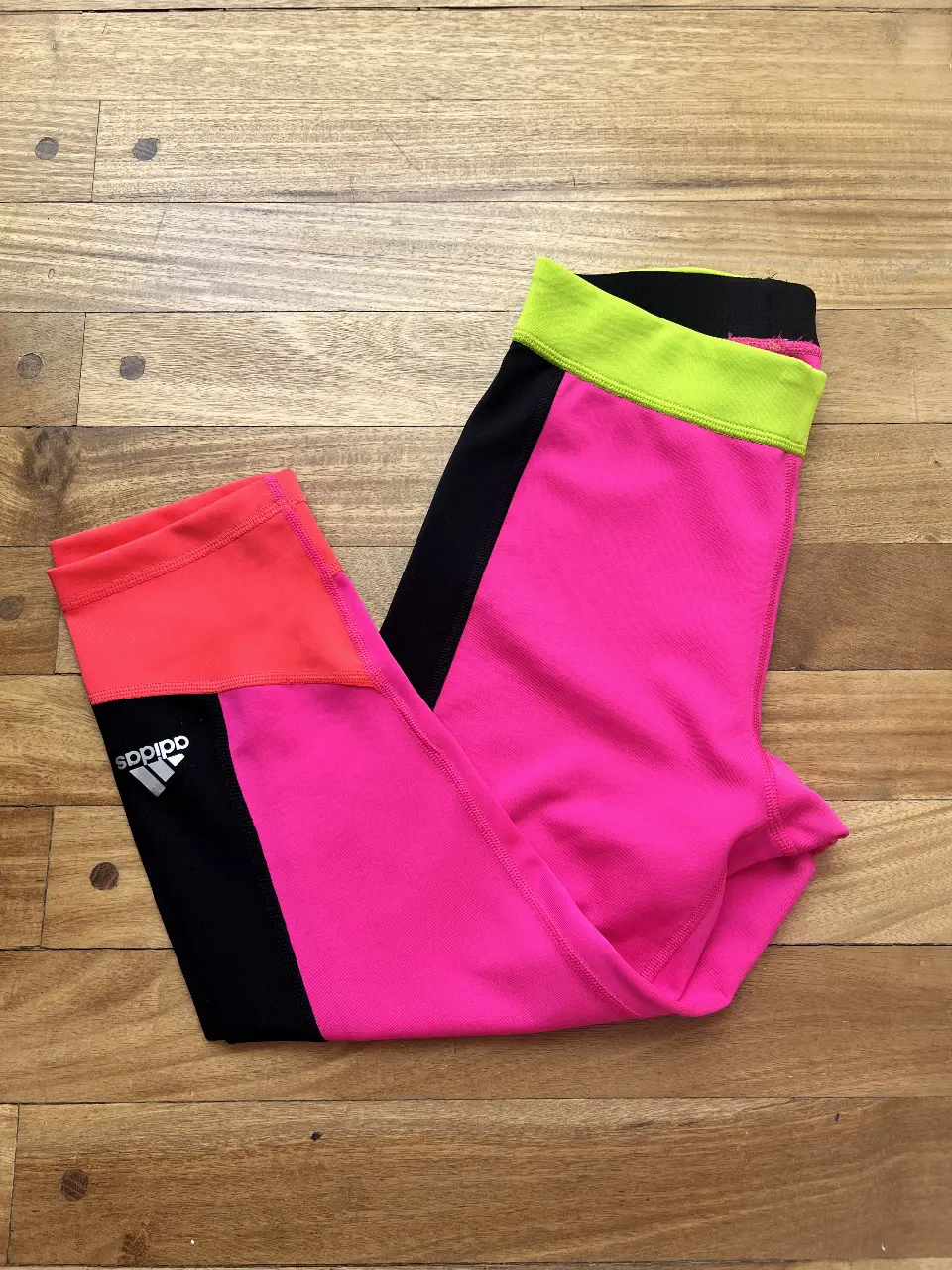 Calzas deportivas Adidas Techfit para mujer, color rosa y negro con detalles en naranja y amarillo. Ideal para entrenamientos de alto rendimiento. ( modelo abajo de la rodilla )