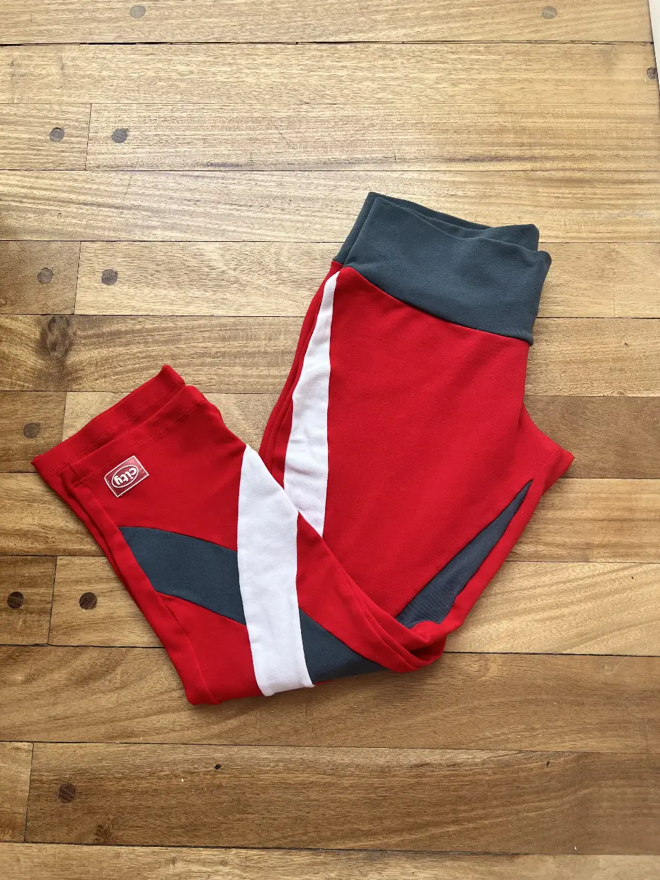 Calzas deportivas de mujer, pescadora, ( abajo de la rodilla ) con diseño en rojo, blanco y gris. Ideales para actividades físicas y entrenamiento. Cómodas y con estilo.