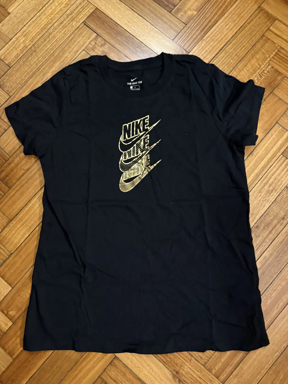 Remera Nike negra con estampado dorado del logo de la marca. Ideal para un look deportivo y casual.