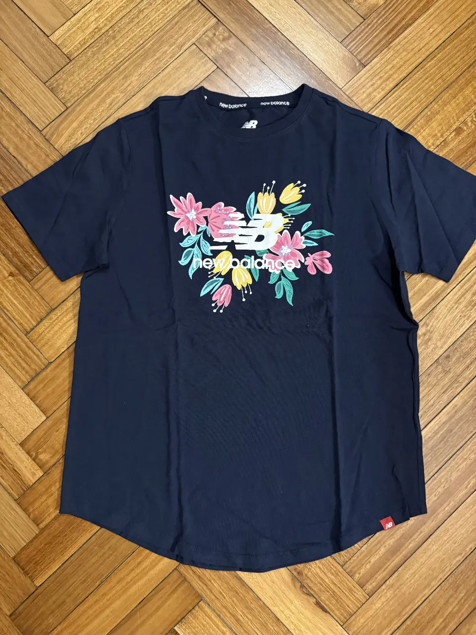 Remera de mujer.  New Balance con estampado floral en el frente. Talle S. Ideal para un look casual y cómodo.