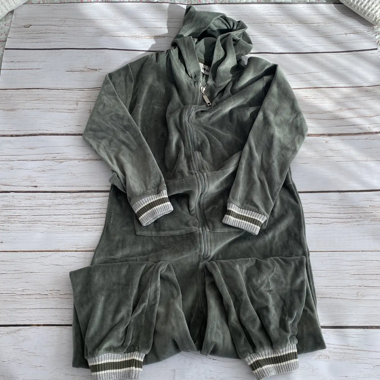 Mono largo/kigurumi/onesie de terciopelo color verde militar con capucha y cierre frontal. Detalles de puños y tobillos con franjas blancas y verdes. pijama