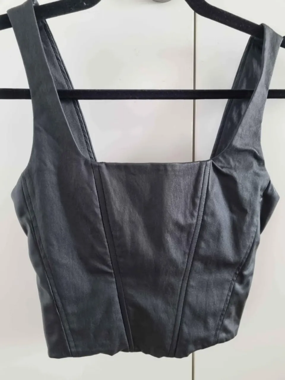 Top negro  Tucci de cuero  sintético con diseño de corset. Ideal para un look moderno y audaz. Cuenta con cierre frontal y tirantes anchos.