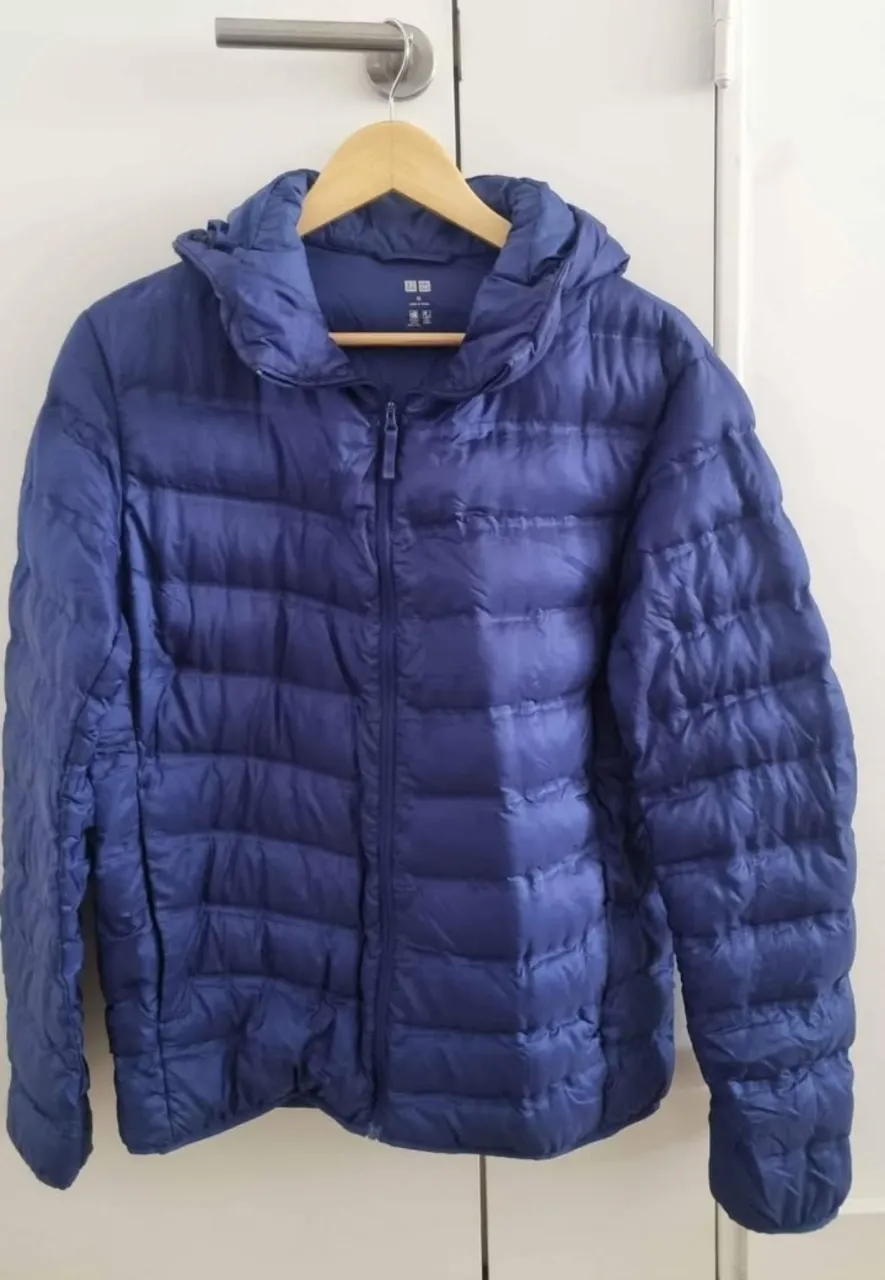 Campera de pluma azul marino de la marca Uniqlo, con capucha y cierre. Ideal para el invierno, ligera y fácil de guardar.