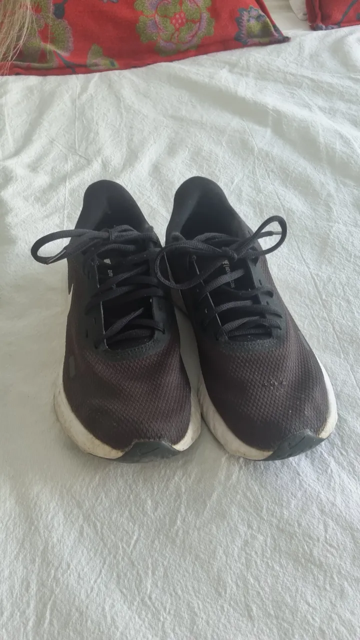 Zapatillas Nike Revolution 5 negras con detalles en blanco. Ideales para running y uso diario. Cómodas y con diseño moderno.