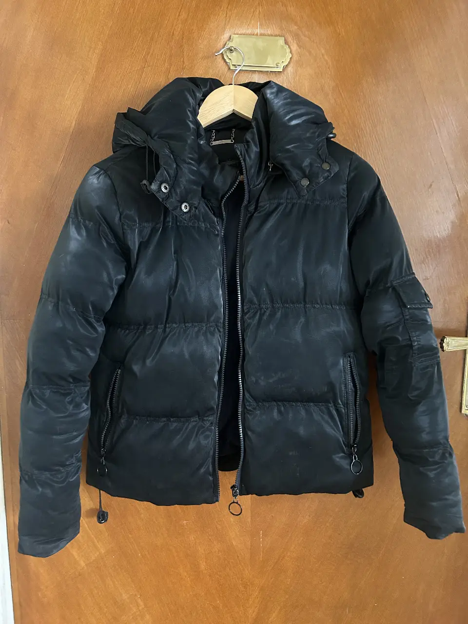 Campera puffer negra, ideal para el invierno. Con capucha, bolsillos y cierre. Perfecta para un look casual y abrigado.