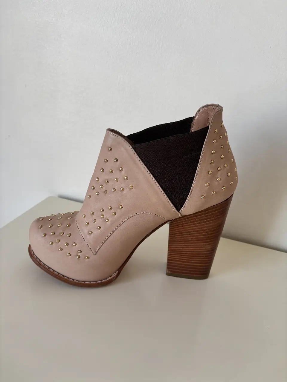 Botines de mujer color crudo con detalles dorados y taco de madera. Ideales para un look casual y moderno.