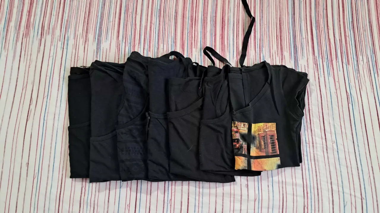 Lote de 7 remeras y musculosas negras. Incluye una remera con estampa de Londres, una musculosa con botones y otra con diseño de rombos. Ideales para el día a día o para entrenar.