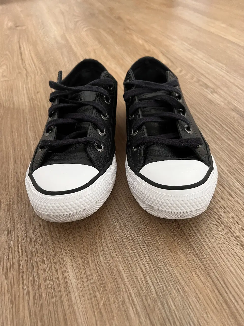 Zapatillas Converse All Star negras de cuero con puntera blanca. Ideales para un look casual y urbano.