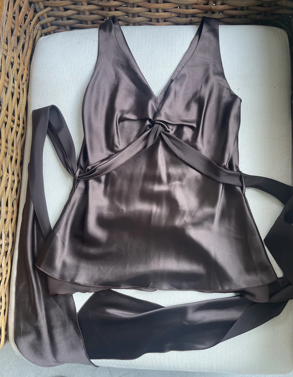 Top de seda marrón con escote en V y detalle de lazo anudado en el frente. Breteles finos y corte acampanado. Ideal para un look elegante y sofisticado.