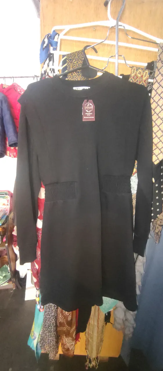 Vestido midi negro, con detalle fruncido en la cintura y mangas largas. Ideal para un look casual y moderno.