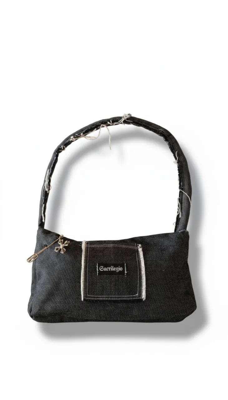 Cartera de jean negro, estilo baguette shoulder bag con detalles desgastados y un charm de cruz plateado. Bolsillo chico interior. Ideal para un look urbano y canchero. 