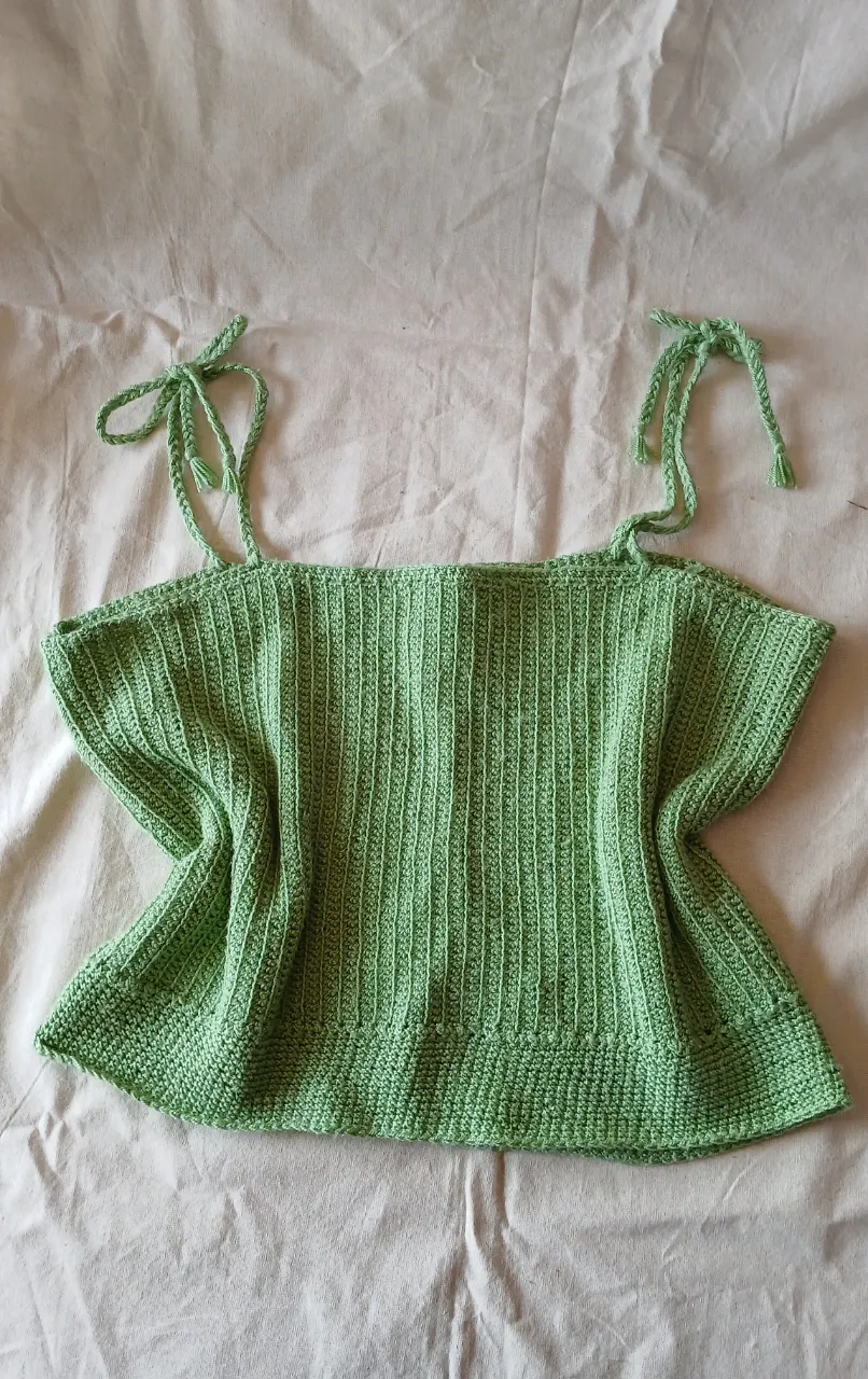 Top tejido al crochet, color verde menta. Posee tiras regulables con nudos y un diseño acanalado que le da elasticidad