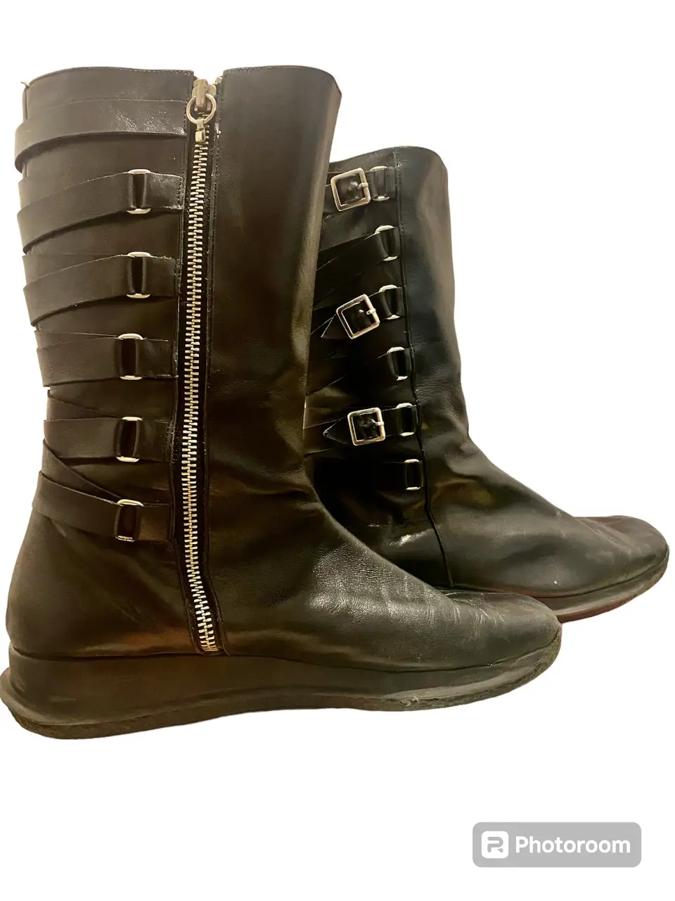 Botas de cuero negro con cierre lateral y detalles de hebillas y correas. Diseño moderno y audaz, ideales para un look rocker o urbano.