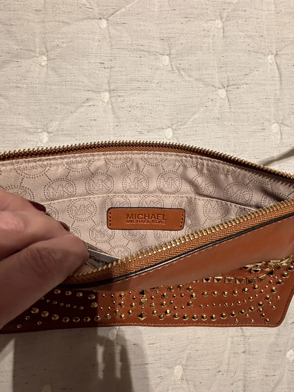 Cartera sobre de cuero marrón con tachas doradas. Ideal para eventos y salidas. Diseño elegante y moderno.