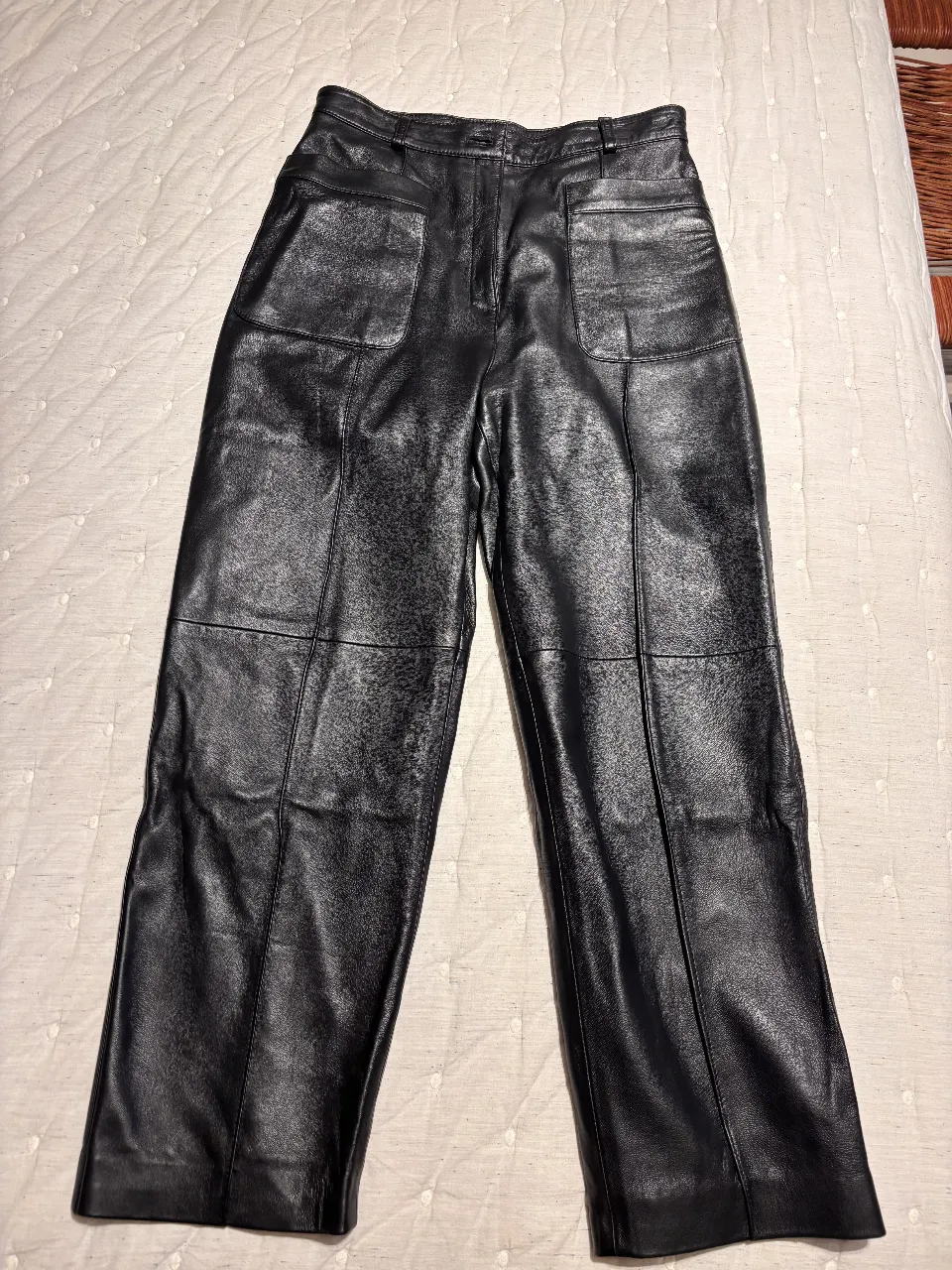 Pantalón de cuero negro, tiro alto, con bolsillos delanteros y detalles de costuras. Talle 3 de la marca Ginebra. Ideal para un look elegante y moderno.