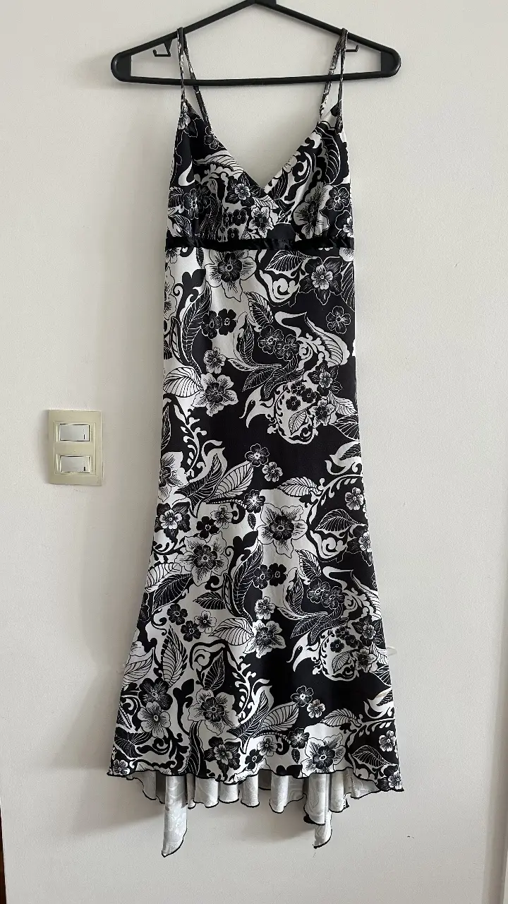 Vestido largo de fiesta con estampado floral en blanco y negro. Diseño elegante con tirantes finos y detalle de cinta en la cintura. Ideal para eventos especiales.