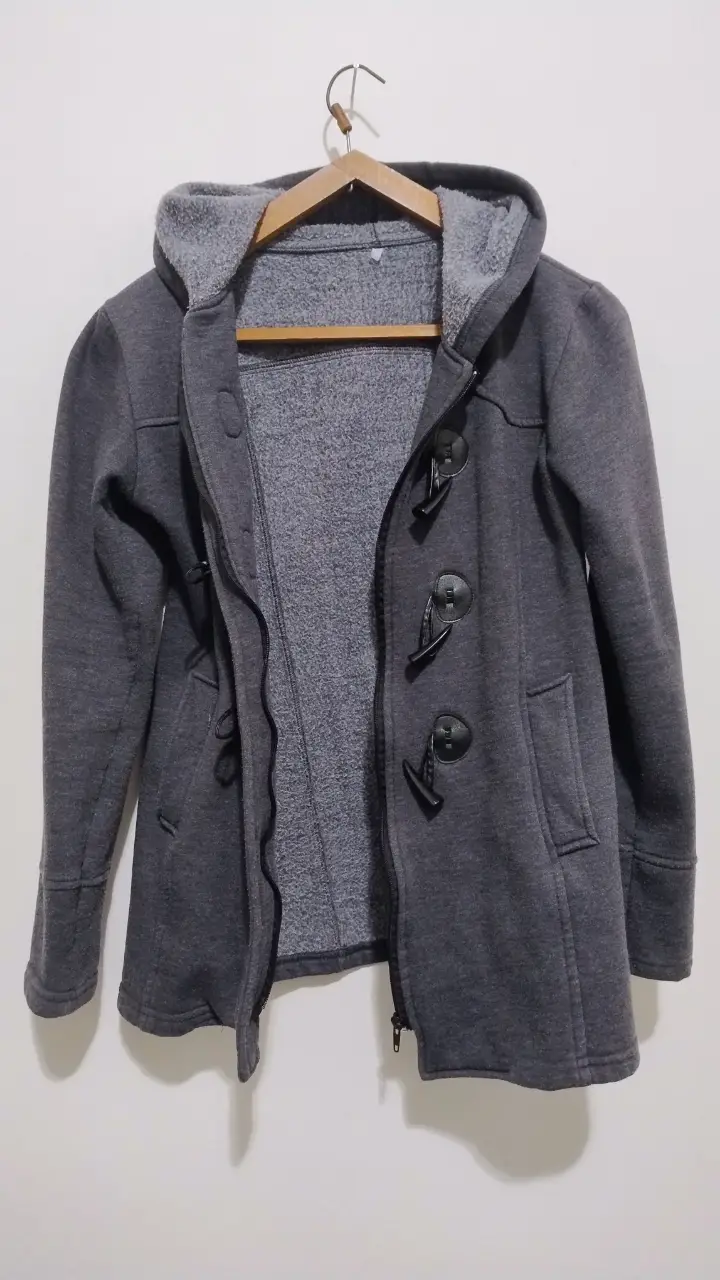 Abrigo con capucha de color gris oscuro, con botones tipo duffle coat y cierre frontal. Ideal para un look casual y abrigado.