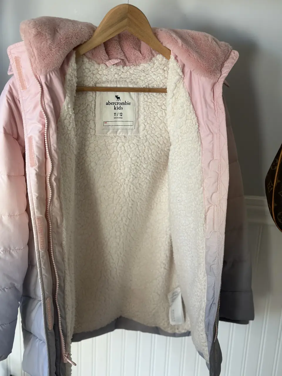 Campera de abrigo para niña, con capucha y forro de piel sintética. Diseño degradado en tonos rosa y gris. Marca Abercrombie Kids. Talle 11/12.