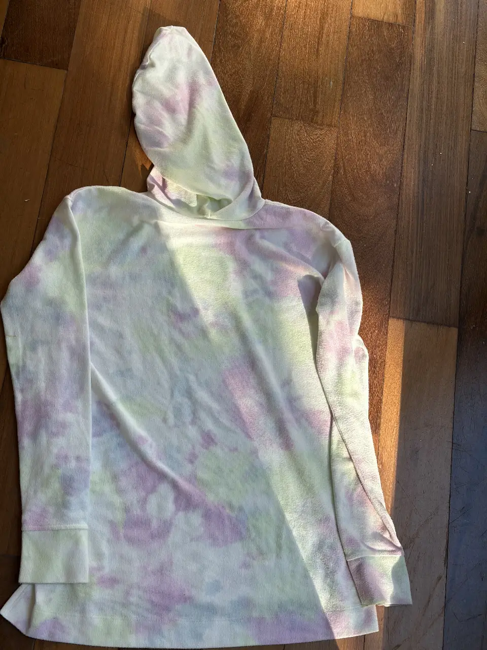 Buzo canguro para niña, con capucha y estampado tie dye en tonos pastel. Ideal para un look casual y cómodo.