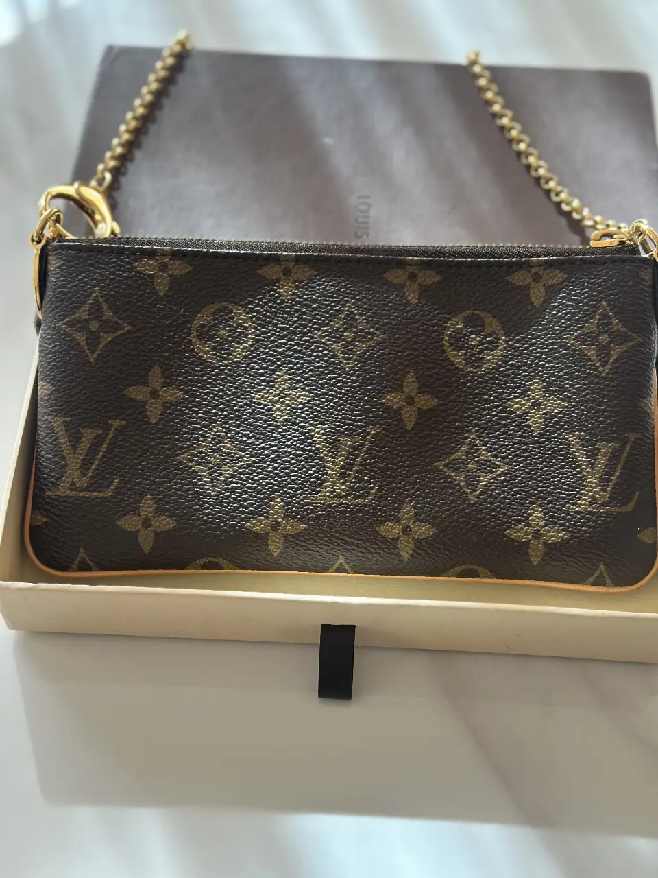 Cartera Louis Vuitton Pochette Accessoires en lona Monogram marrón con cadena dorada. Ideal para llevar tus esenciales con estilo y elegancia.