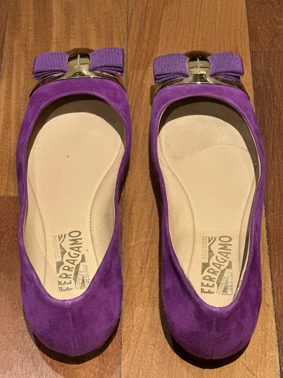 Ballerinas de gamuza violeta con moño y detalle dorado de la marca Ferragamo. Un calzado elegante y cómodo para cualquier ocasión.