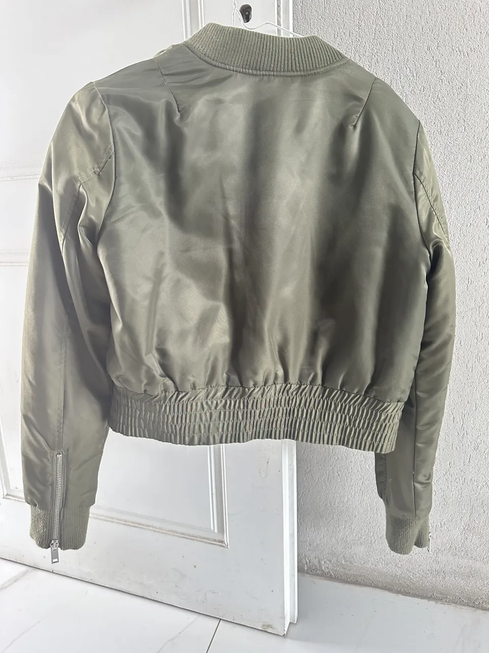 Campera bomber verde con cierre al frente y bolsillos laterales con cierre. Puños y cintura elastizados.