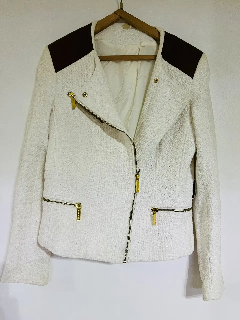 Campera estilo biker en color blanco con detalles en marrón en los hombros. Posee cierre y bolsillos con detalles dorados. Ideal para un look elegante y moderno.