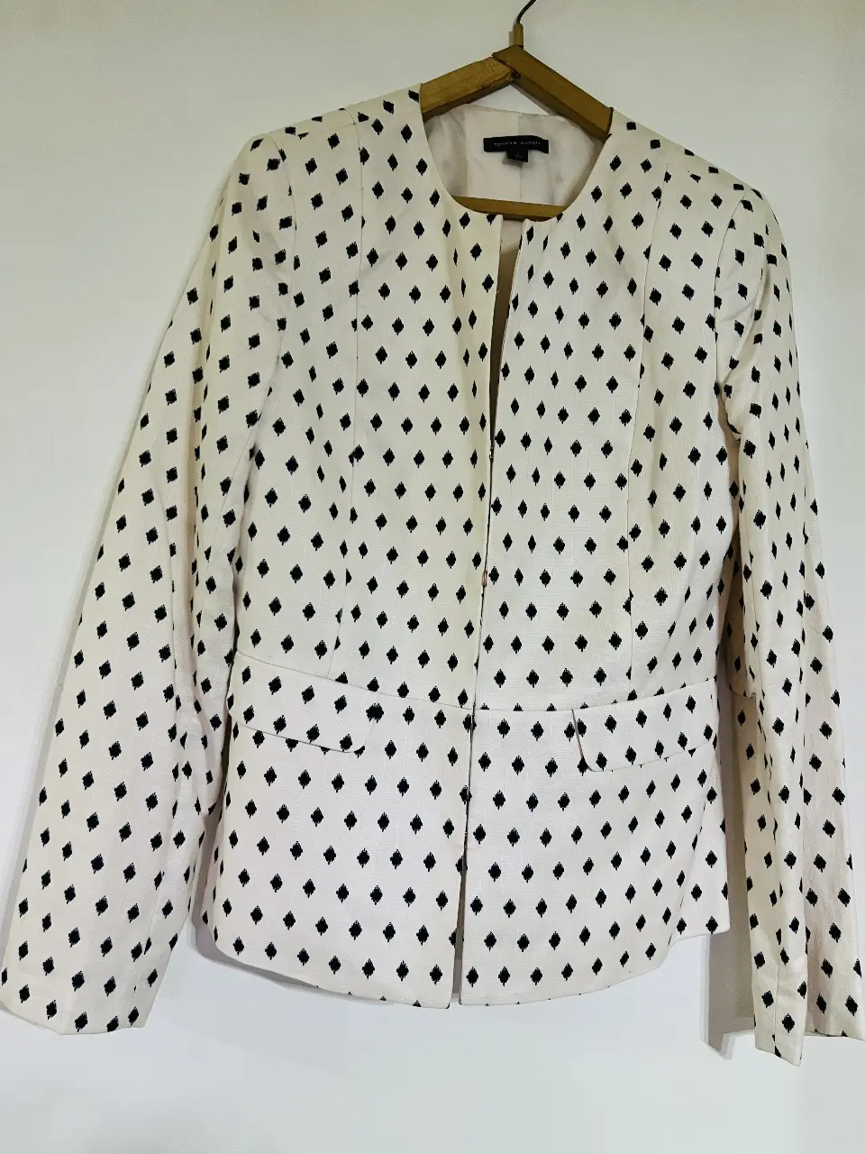 Blazer blanco con estampado de rombos negros. Corte entallado, con dos bolsillos delanteros y solapas. Ideal para un look elegante y moderno.
