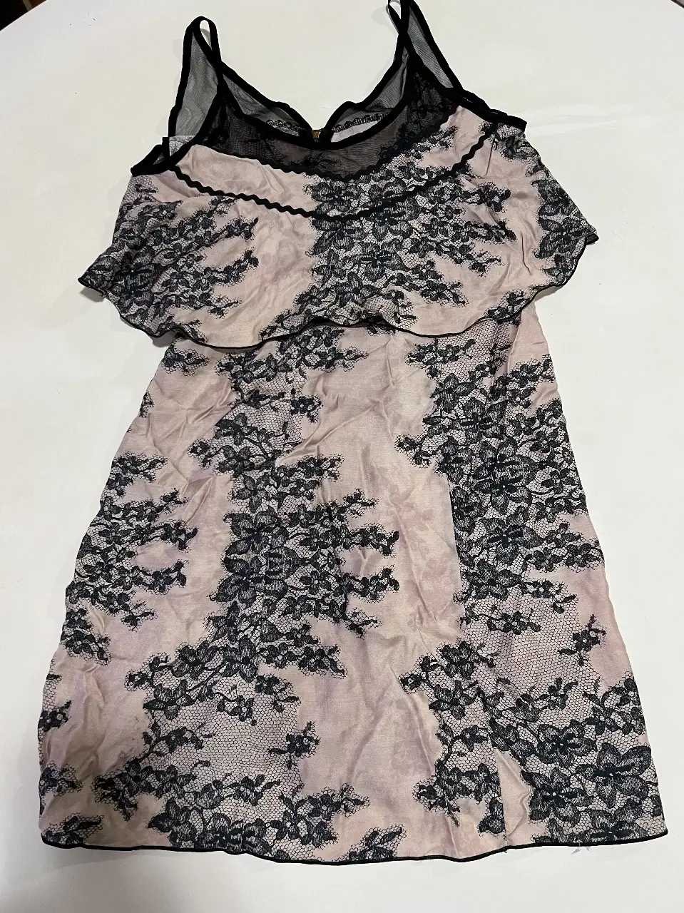 Vestido mini de encaje rosa con detalles en negro. Ideal para una salida especial o una fiesta. Diseño elegante y romántico.