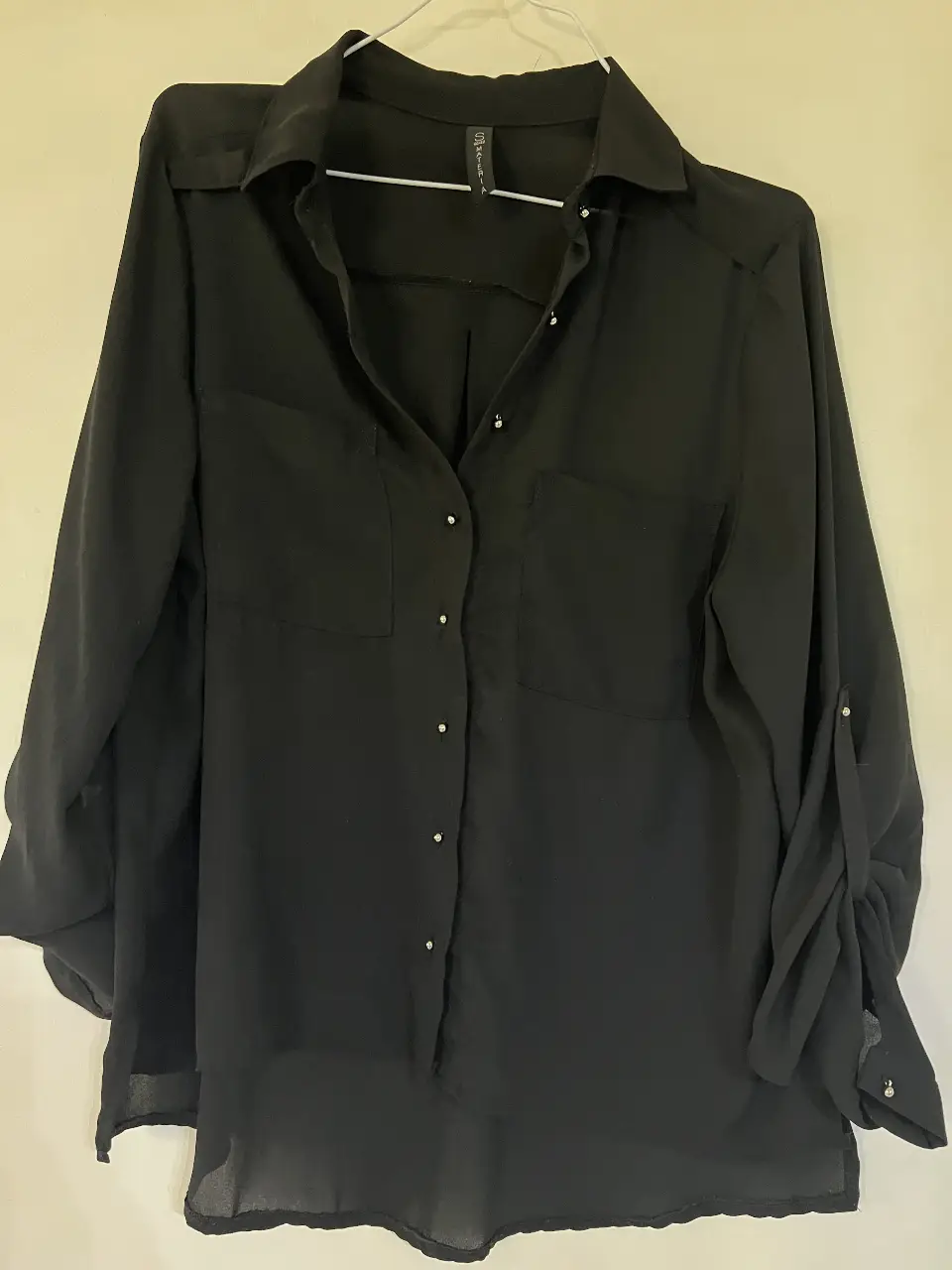 Blusa negra de manga larga con botones y bolsillos delanteros. Ideal para un look elegante y versátil.
