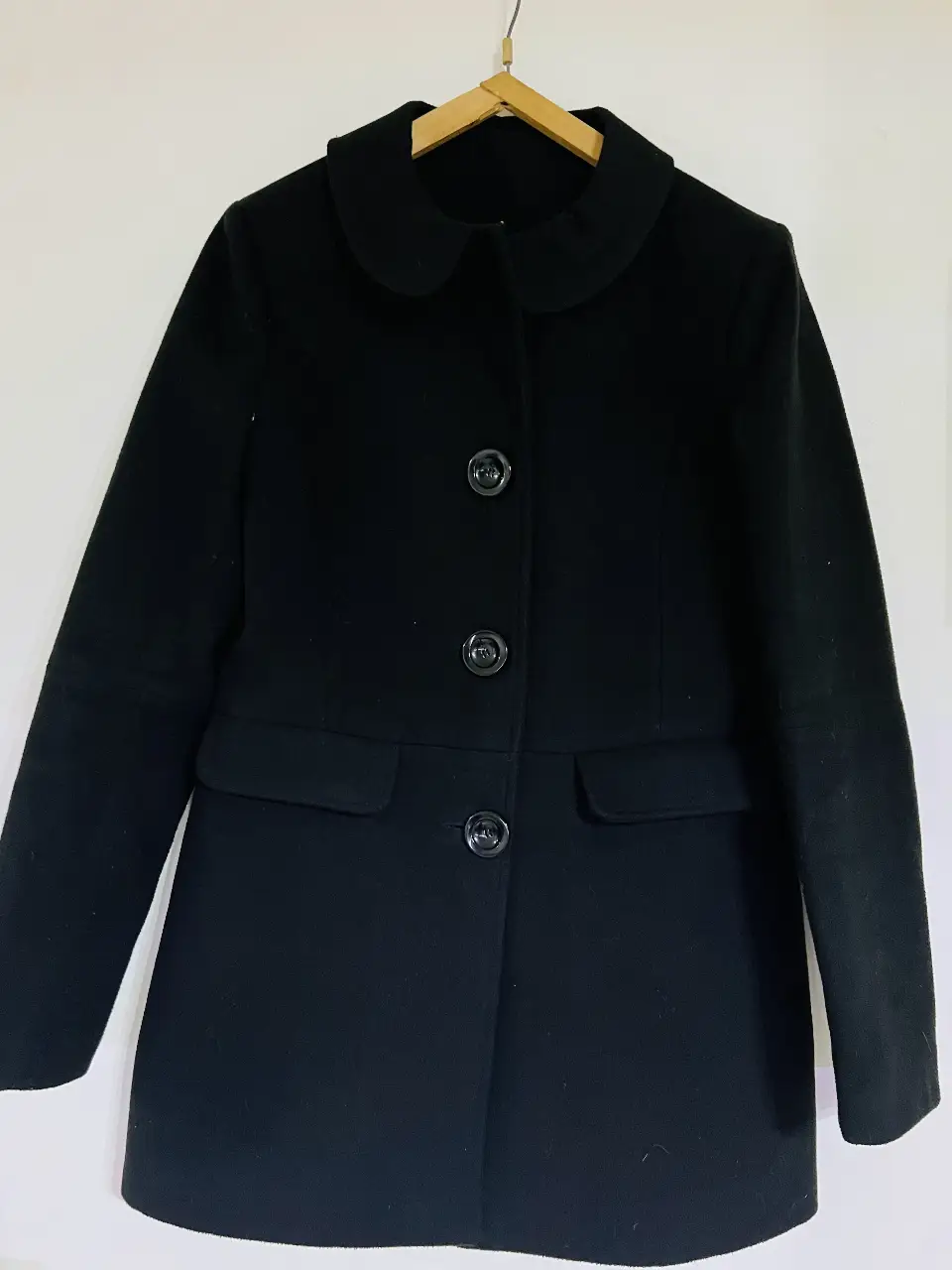 Tapado negro de paño con cuello redondo y botones. Ideal para un look elegante y abrigado en invierno. Perfecto para combinar con diferentes outfits.