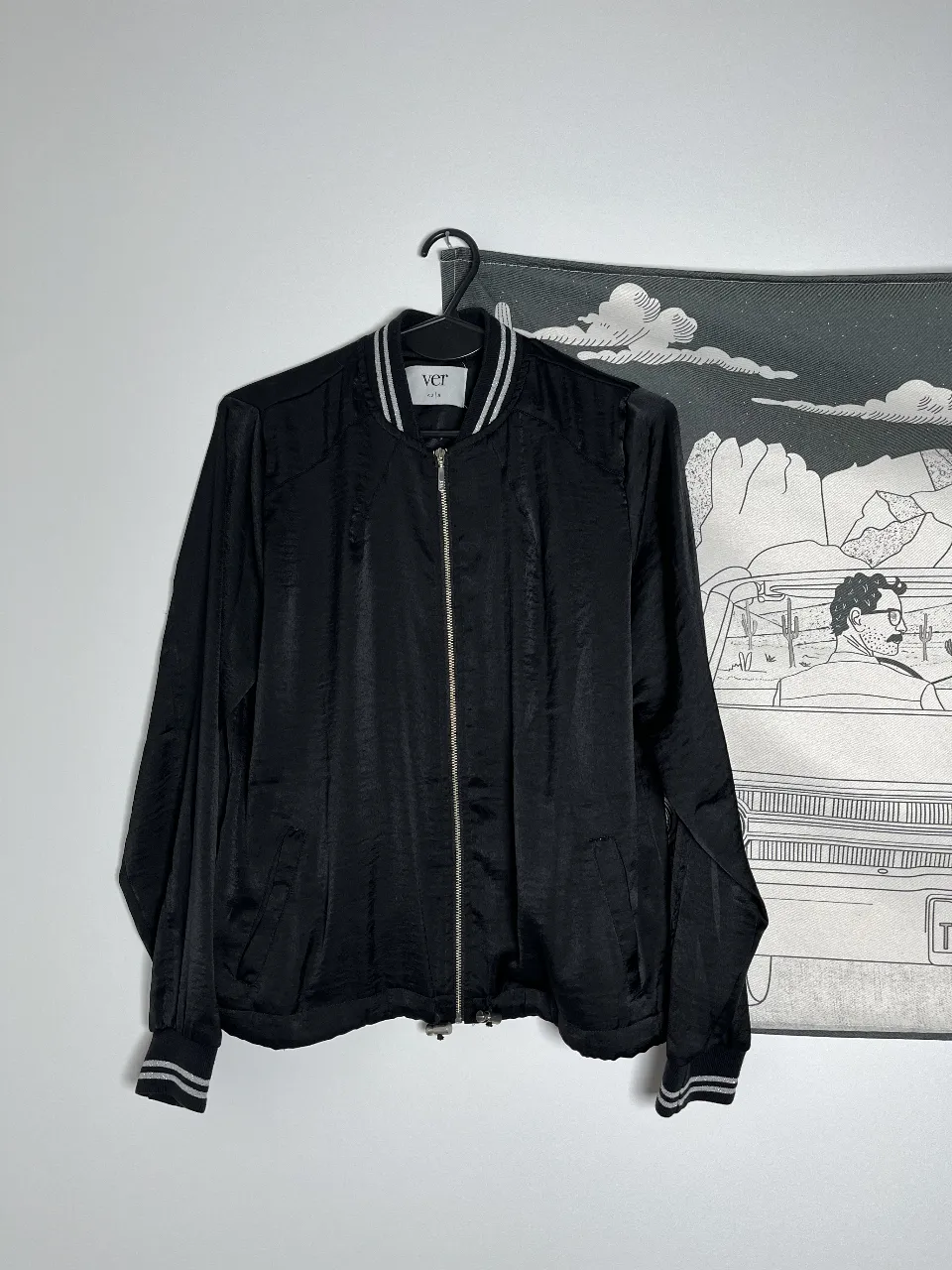 Campera bomber negra de mujer, con detalles en blanco y gris en cuello y puños. Cierre frontal y diseño elegante para un look casual.