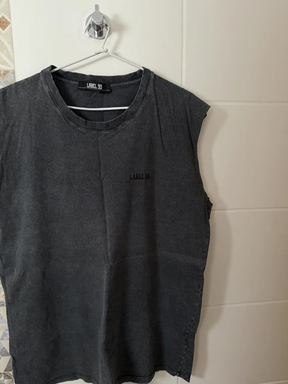 Musculosa gris oscuro con logo de la marca bordado en el frente. Cuello redondo y sin mangas.