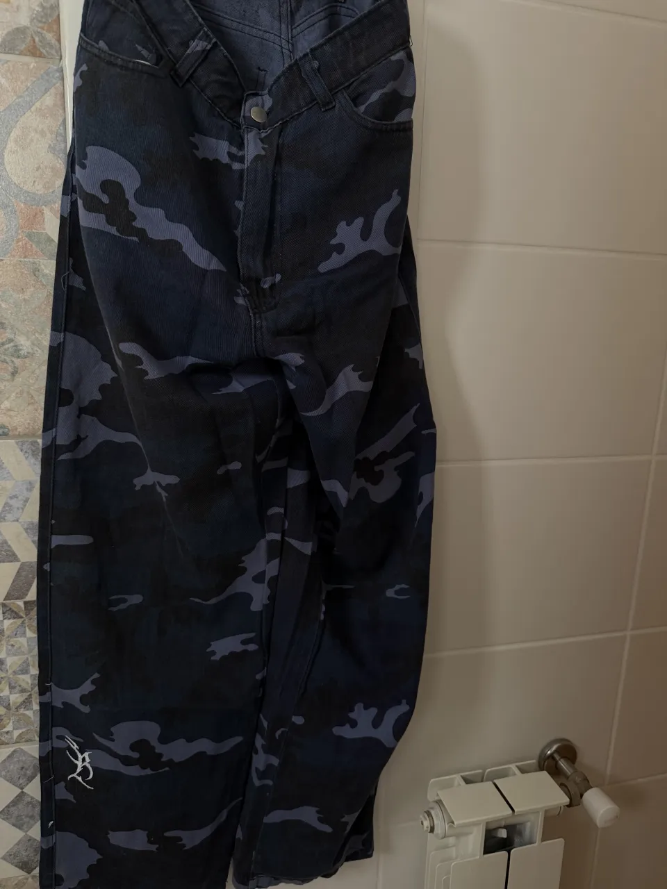 Pantalón de jean con estampa camuflada en tonos azules y negros. Posee logo bordado en la parte frontal y marca visible en etiqueta.