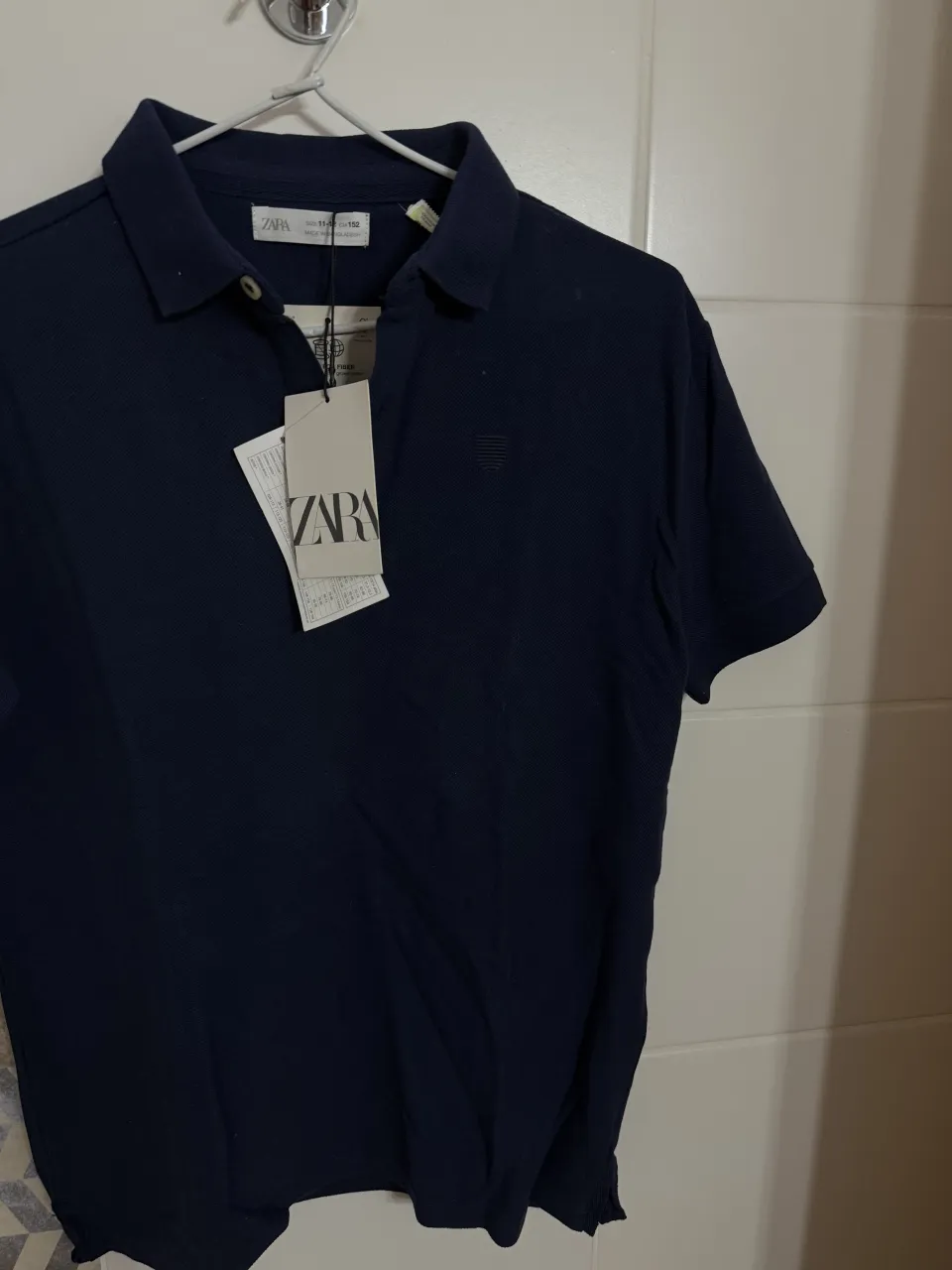 Remera azul marino de manga corta con cuello polo y dos botones. Tiene un pequeño logo bordado en el pecho.