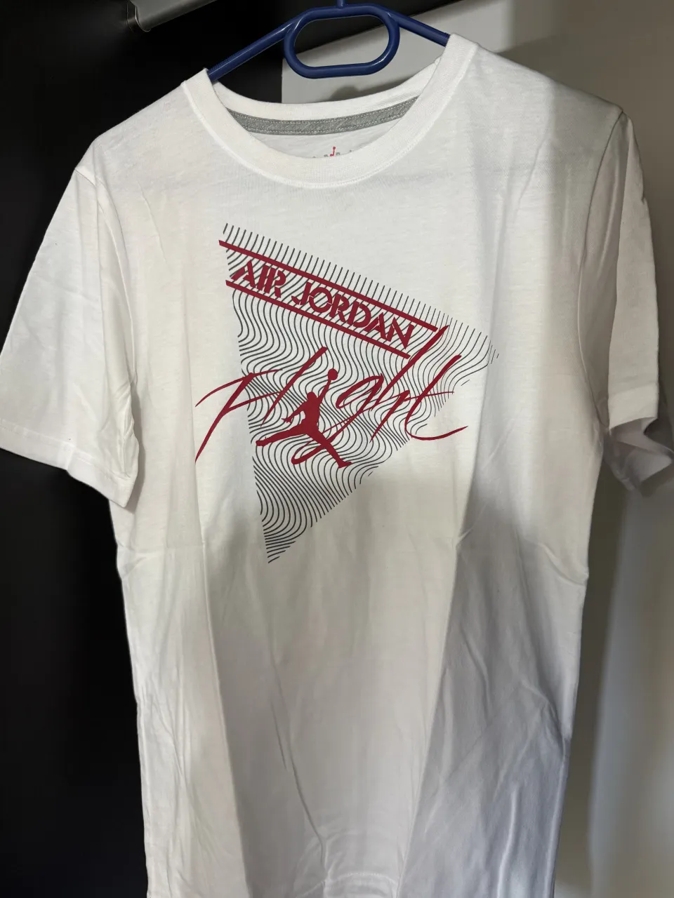 Remera blanca de manga corta con estampa de "Air Jordan Flight" en rojo y negro.