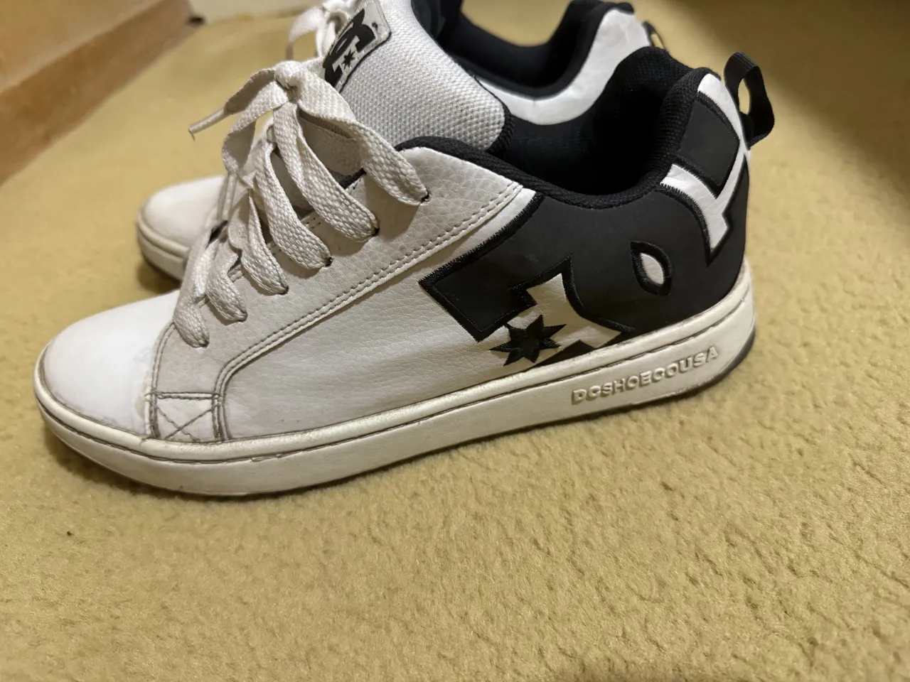 Zapatillas urbanas blancas con detalles en negro. Poseen cordones blancos y suela negra.