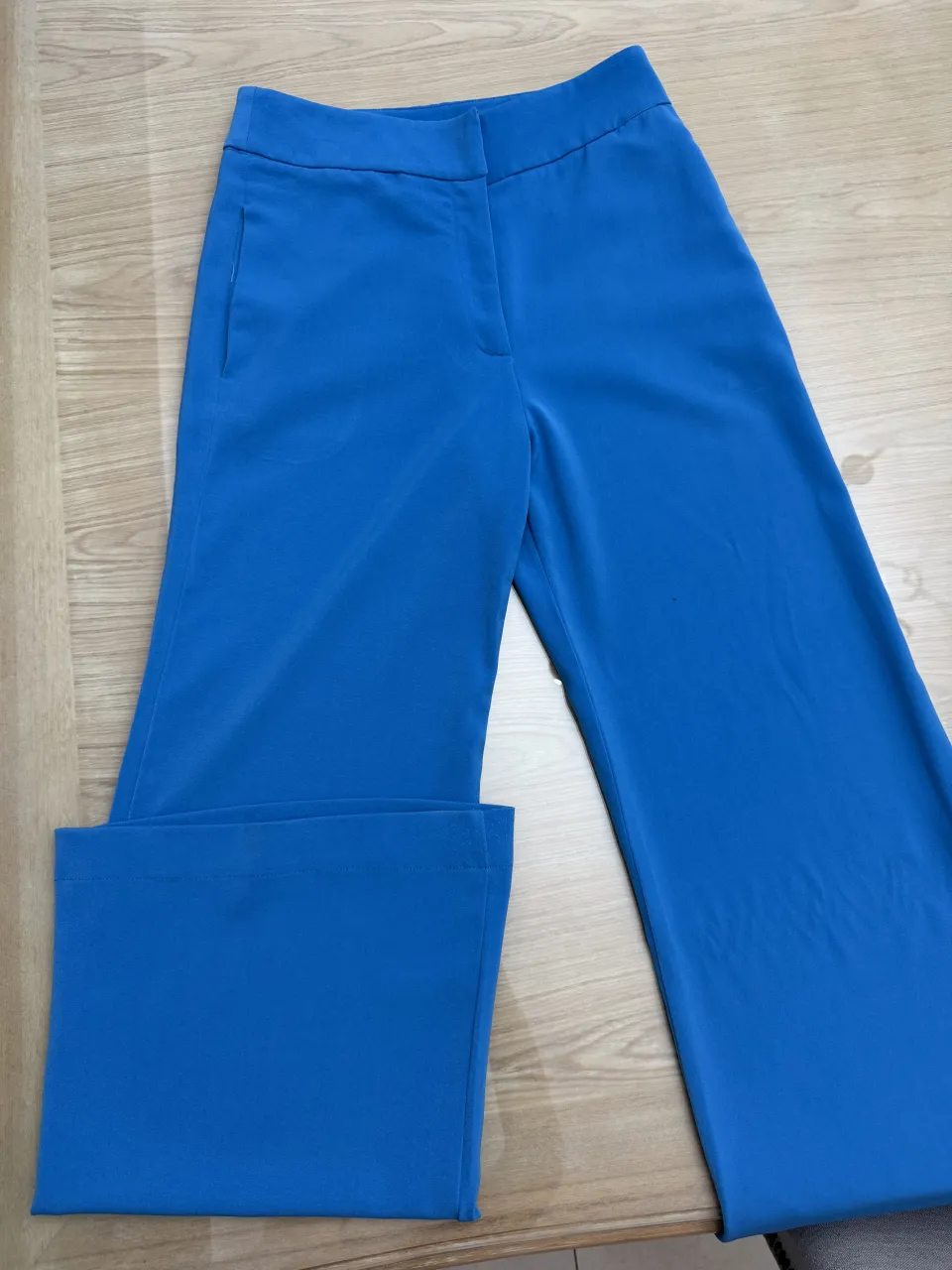 Pantalón azul de vestir, tiro alto, con bolsillos delanteros y pierna ancha.