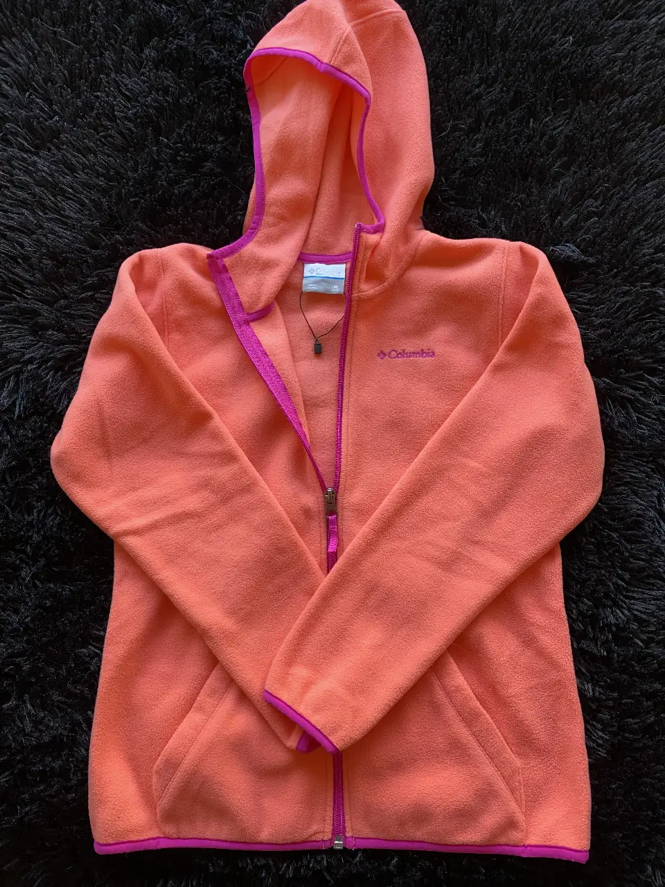 Buzo de Polar con capucha y cierre frontal para niña, de color naranja con detalles en rosa. Marca Columbia, talle M (10/12). Ideal para actividades al aire libre.
