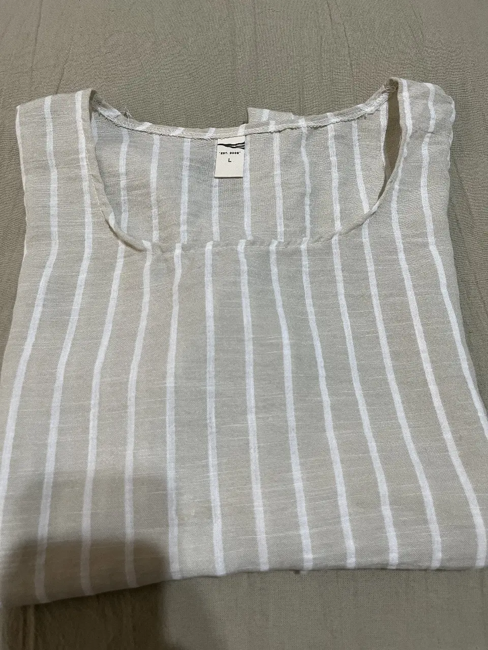 Blusa de lino a rayas verticales en tonos beige y blancos, con cuello redondo y mangas cortas con dobladillo. Ideal para un look fresco y casual.