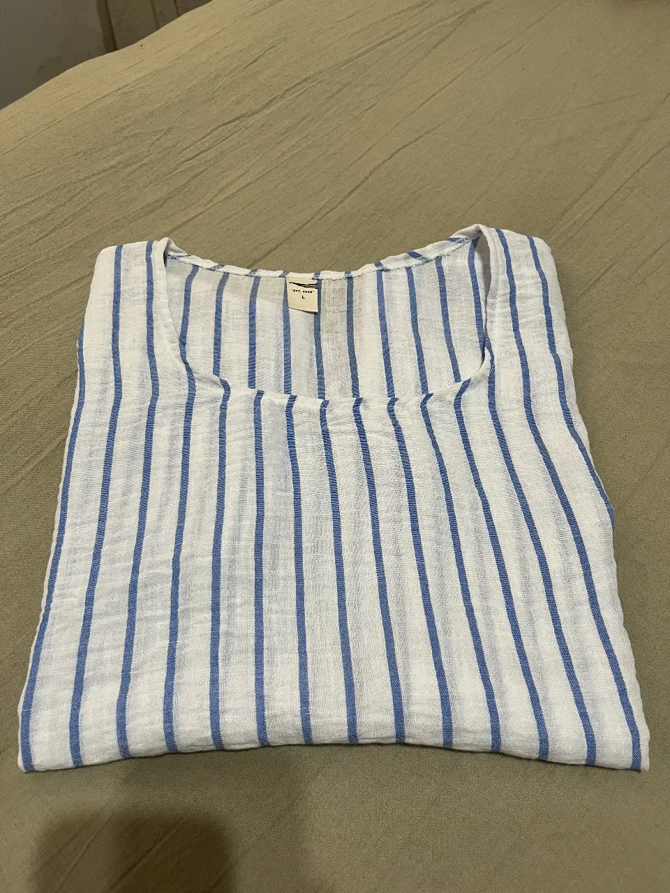 Blusa de lino a rayas verticales en blanco y azul, con cuello redondo y mangas cortas. Ideal para un look fresco y casual.