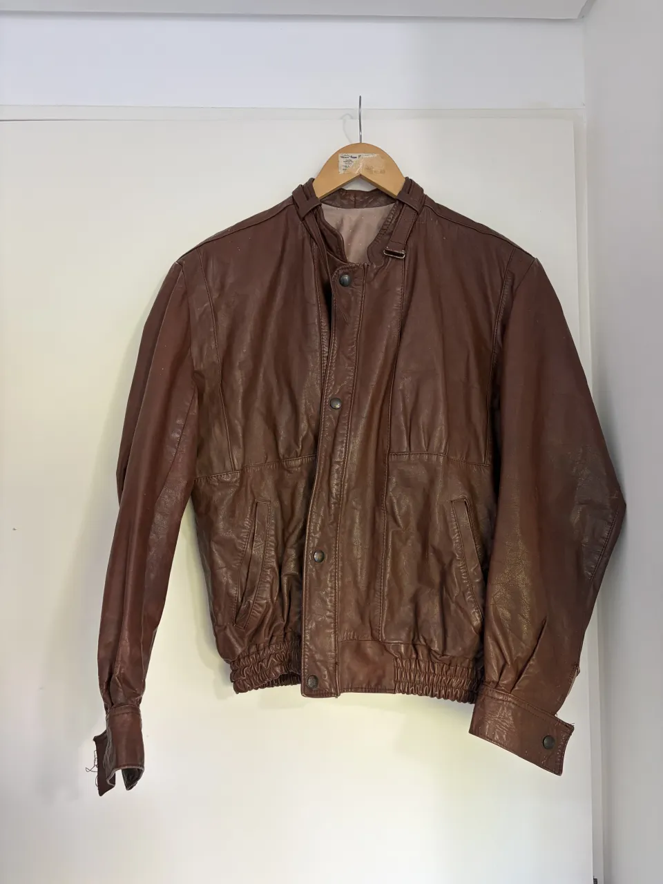 Campera de cuero marrón con cuello mao, cierre y botones a presión. Posee bolsillos frontales con solapa y puños ajustados con botón a presión. El interior es forrado y tiene un bolsillo.