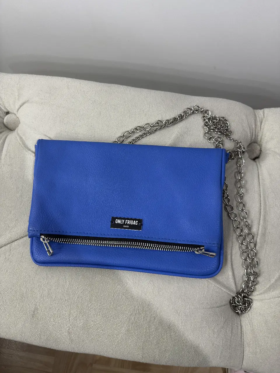 Cartera bandolera azul de Only Fridac, ideal para un look casual y moderno. Confeccionada en material similar al cuero, cuenta con un cierre y una cadena plateada para llevarla al hombro. Perfecta para llevar tus esenciales con estilo. 1 solo uso